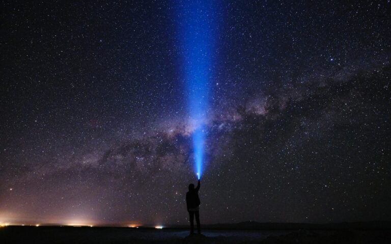 silhouette of man standing on seashore under starry night